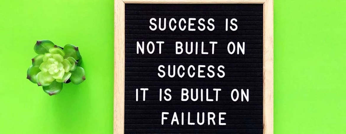 A quote that is written on a black board which says "Success is not built on Success, it is built on failure"