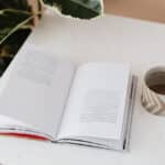 Coffee table book is kept on a table next to a cup of coffee