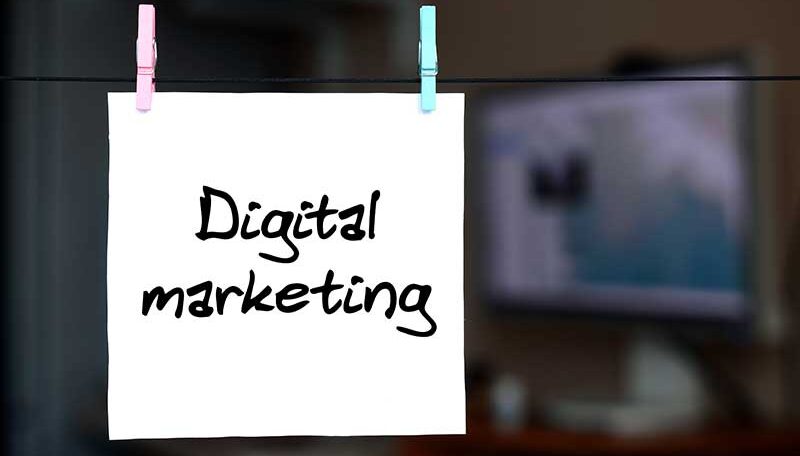 Digital marketing. Note is written on a white sticker that hangs with a clothespin on a rope on a background of office interior
